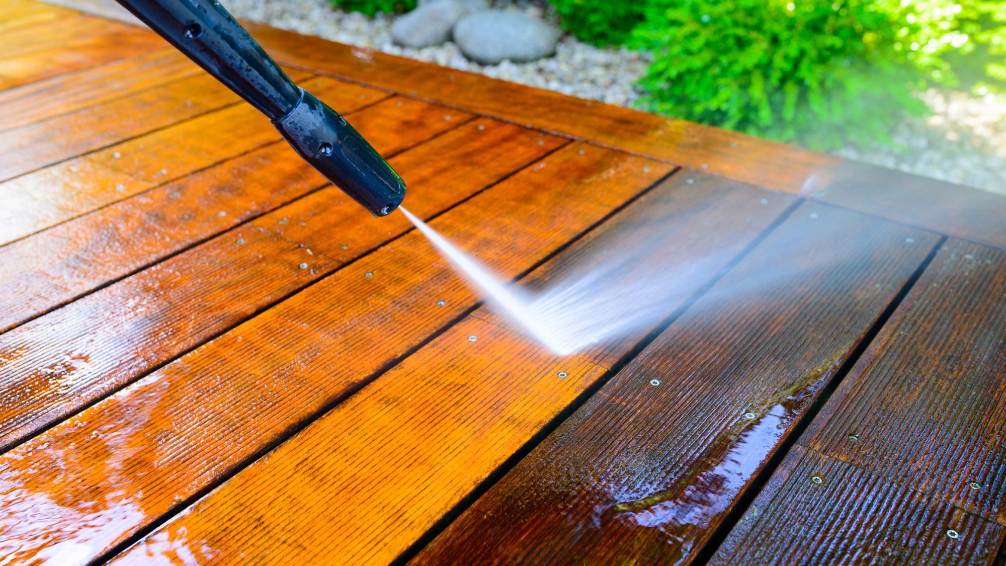 Cleaning terrace with a power washer - high water pressure cleaner on wooden terrace surface